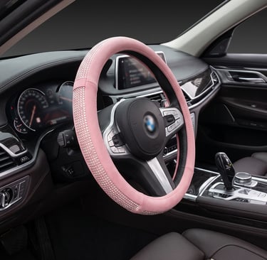 Luxury pink rhinestone steering wheel cover installed on a black leather car interior for a stylish sparkle.