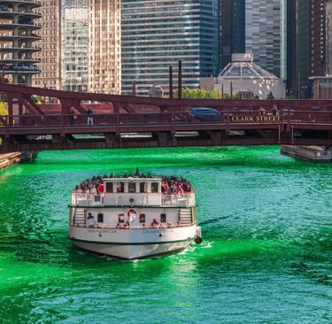 A white tour boat cruises on the bright green Chicago River for Saint Patrick's Day.