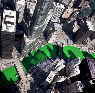 Aerial view of the bright green Chicago River during St. Patrick's Day celebrations surrounded by city skyscrapers.