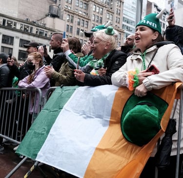 Crowds celebrate St. Patrick's Day in New York City with an Irish flag and green festive hats.