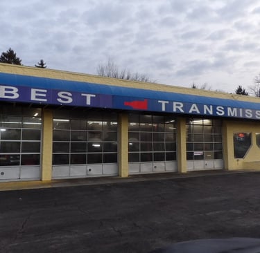 Exterior of Best Transmission auto repair shop with multiple service bays and blue awning.