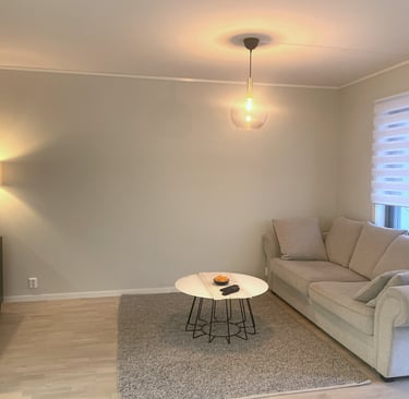 Modern living room featuring a beige sofa, round coffee table, and warm lighting with a glass pendant lamp.
