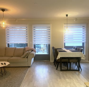 Modern open plan living room and dining area with neutral sofa, wooden floors, and white stripes.