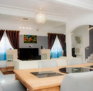 Salon-salle à manger moderne : table en bois, canapés en cuir blanc et arche.