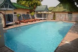 Piscine de Villa de luxe à kribi avec chaises longues et terrasse en bois en zone tropicale.