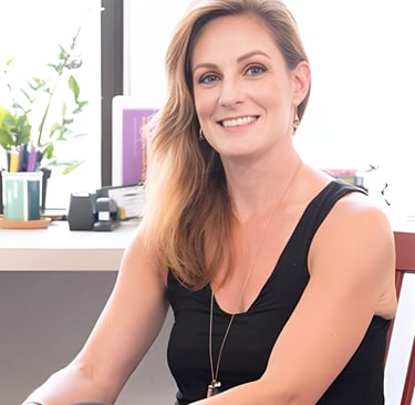 Smiling female professional in a black sleeveless top sitting in a bright modern office.