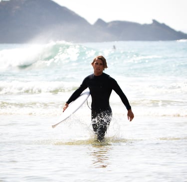 a man in a wetsuit is holding a surfboard