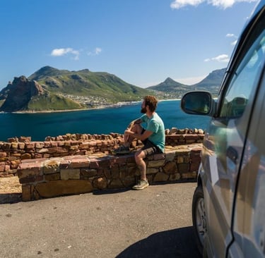a man sitting on a ledge overlooking a body of water