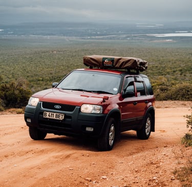 a red car with a large luggage bag on top of it