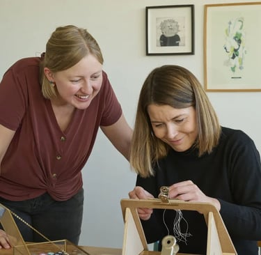 Dos mujeres sonrientes creando joyería artesanal hecha a mano en un estudio creativo con luz natural