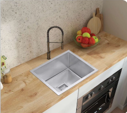 Modern stainless steel undermount kitchen sink installed in a light wood countertop with a tall pull-down faucet.