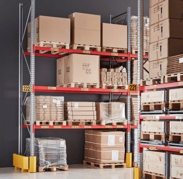 Industrial warehouse storage racks with cardboard boxes on pallets for organized distribution.