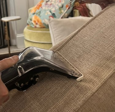 Professional upholstery cleaning technician using steam extraction tool on beige sofa fabric in Denv