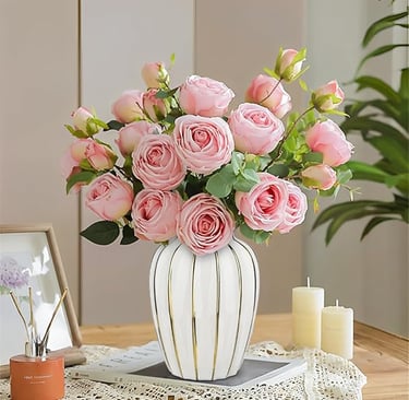 Gold and white ceramic vase filled with soft pink roses, modern luxury flower arrangement.