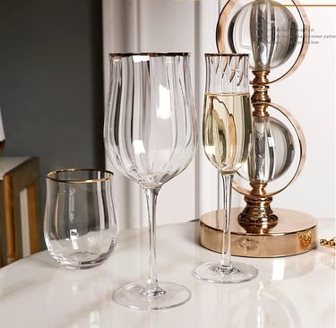Set of clear wine glasses with elegant gold rims on a styled dining table.