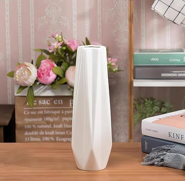 Tall white ribbed ceramic vase filled with blush pink flowers, elegant home styling piece.