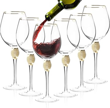 Red wine being poured into gold-stem wine glasses, elegant luxury glassware set.