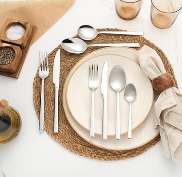 White stainless steel cutlery set styled on natural woven placemat.