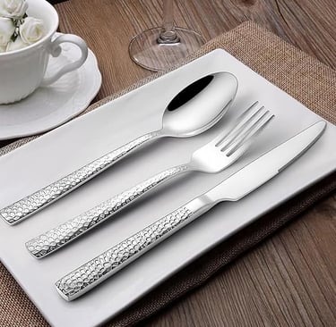 Silverware cutlery set arranged on modern white ceramic tableware.