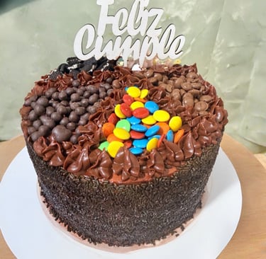 Pastel de cumpleaños de chocolate con chispas, caramelos y un adorno de pastel Feliz Cumple.