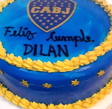 Un pastel de cumpleaños temático de Boca Juniors azul y amarillo con un logotipo de CABJ y glaseado 