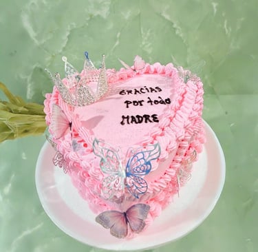 Pastel rosa en forma de corazón del Día de la Madre decorado con una corona, mariposas y texto en es