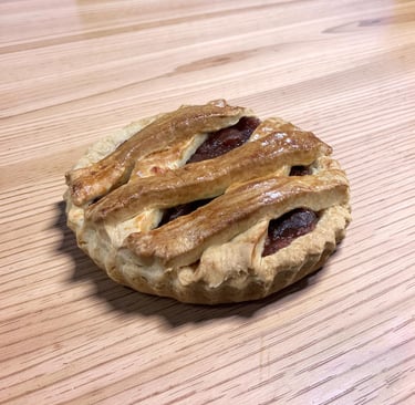 Mini tarta de manzana recién horneada con una corteza de celosía dorada sobre una mesa de madera lig