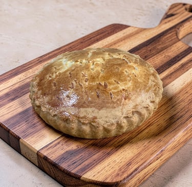 Pastel de carne casero marrón dorado sobre una tabla de cortar de madera con un borde de corteza riz