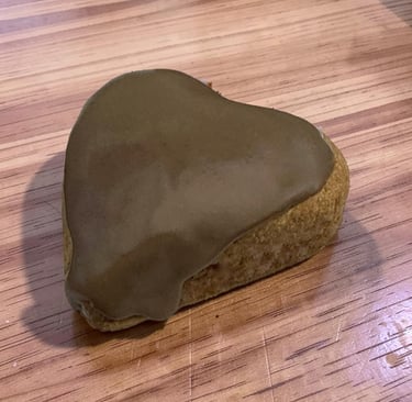 Una galleta de mantequilla en forma de corazón con glaseado de chocolate suave sobre una mesa de mad