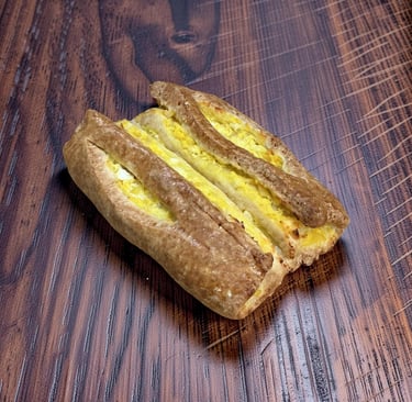 Hojaldre marrón dorado relleno de ensalada de huevo cremosa sobre una mesa de madera oscura.