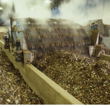 Industrial composting machine processing organic waste with steam in a large-scale recycling facility.