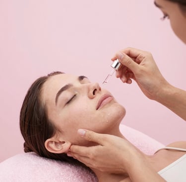 aplicando un sérum facial hidratante con un gotero en el rostro de una mujer durante un tratamiento 