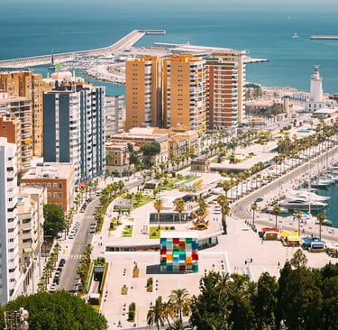 Vista del puerto de Málaga con paseo marítimo, edificios residenciales y el faro de La Farola