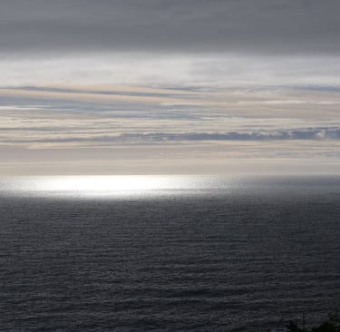 Sunlight reflecting on the Pacific Ocean at Muir Beach with layered clouds and calm coastal California horizon