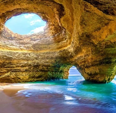 Scenic Benagil Cave in Algarve Portugal with sunlight streaming through the natural skylight onto the beach.