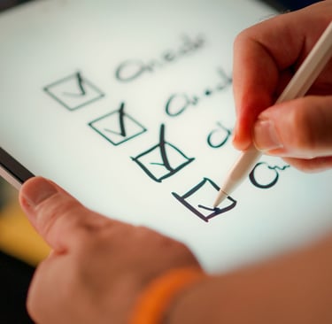 Hand using a white stylus to mark a digital checklist on a tablet screen for task management.