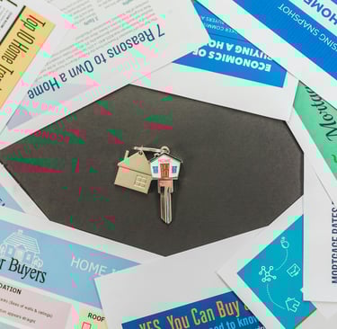 House keys on a keychain centered among real estate market reports and home buying guides.