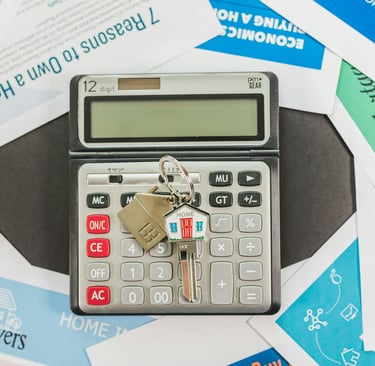 House keys on a digital calculator surrounded by mortgage and home buying financial documents.