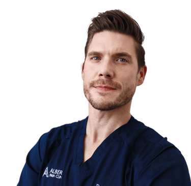 Professional portrait of a male specialist from Albert Pain Clinic wearing blue medical scrubs.