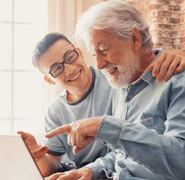 a young man helping an elderly man with a laptop