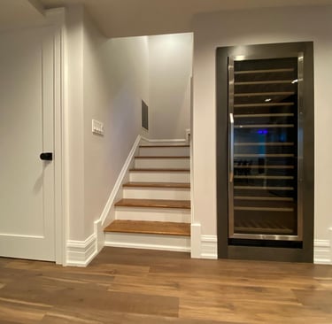 Finished basement featuring staircase with wine cooler installed under the stairs