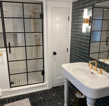 Custom basement shower with glass door, black frame, gold hardware and contemporary freestanding sin