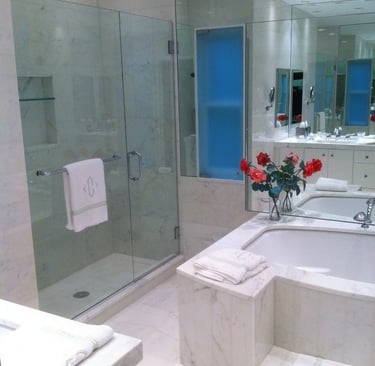 Luxury marble master bath featuring big soaking tub wall mirror, and glass walk-in shower