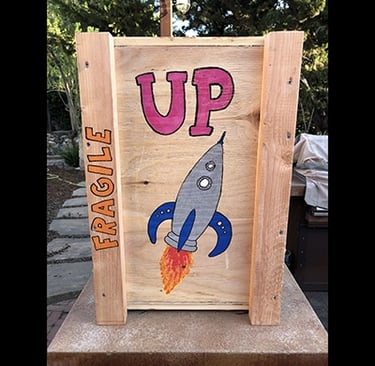 Shipping crate for Talbotics sculpture with image of rocketship drawn on it.