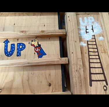 Shipping crates for Talbotics sculpture with image of Underdog and ladder drawn on them.