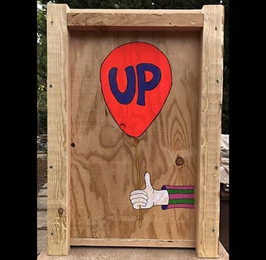 Shipping crate for Talbotics sculpture with image of hand holding a balloon drawn on it.