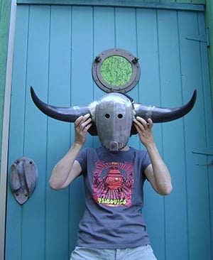 Talbotics t-shirt wearer holding a mask by the studio door.