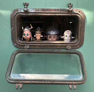 Robot heads peering from Talbotics workshop porthole window.