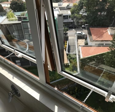 Trava de segurança com corrente limitadora instalada em janela de banheiro sobre a caixa acoplada
