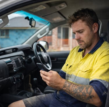 Australian tradie checking jobs from work ute